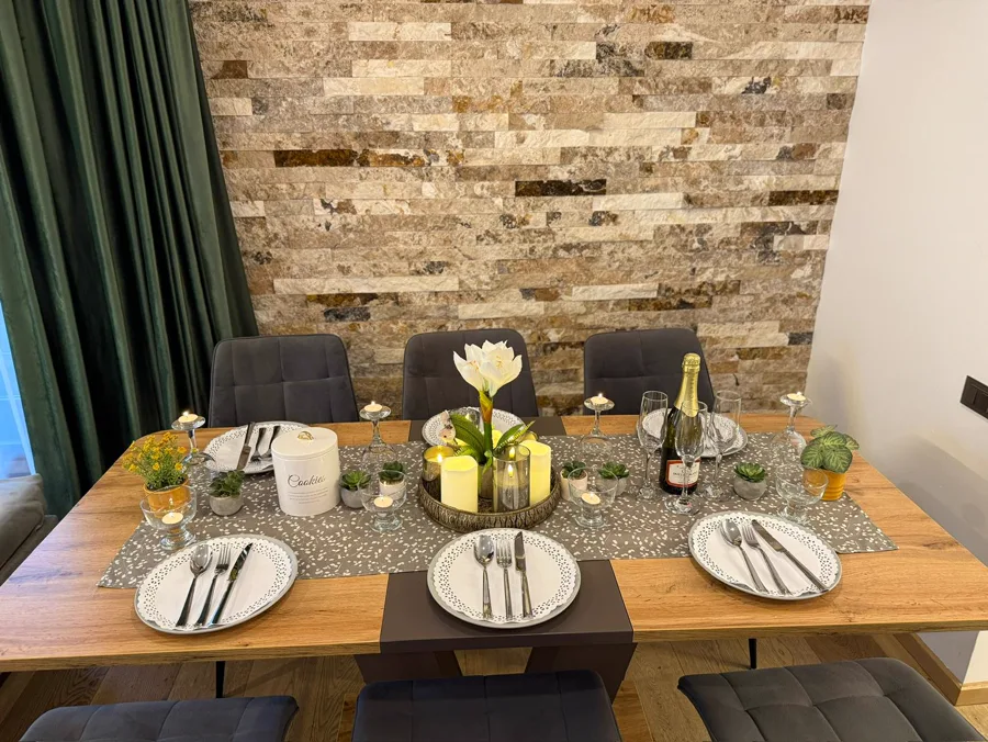 Elegantly set table with stone wall backdrop and glass of red wine